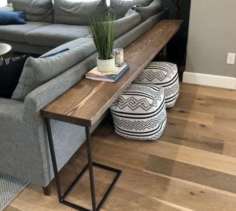 A sofa table is placed behind grey sofa
